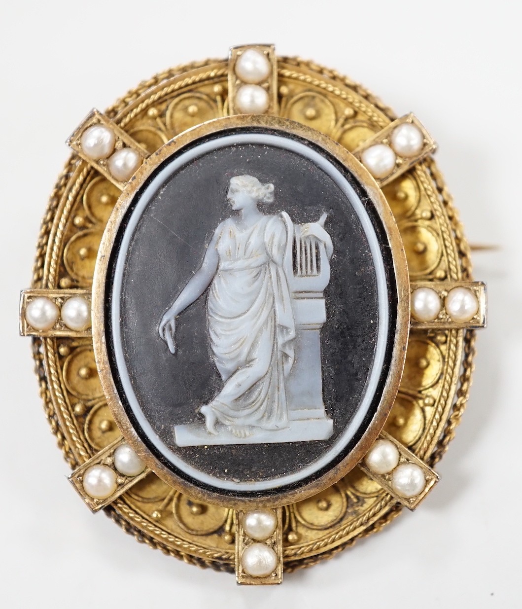 A Victorian canettile work yellow metal and sardonyx? cameo and split pearl set oval brooch, carved with Erato, 38mm, gross weight 8.5 grams.